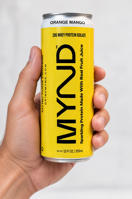 Hand holding a yellow can of MYND Orange Mango sparkling protein water with 20g whey protein isolate.