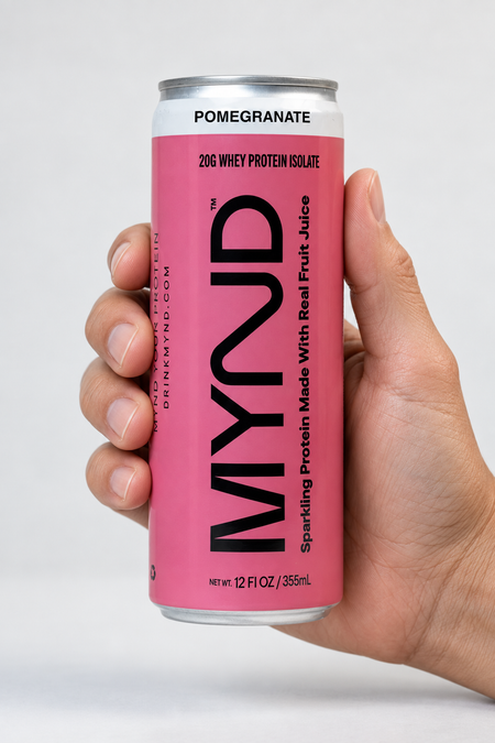 Hand holding a yellow can of MYND Pomegranate sparkling protein water with 20g whey protein isolate.