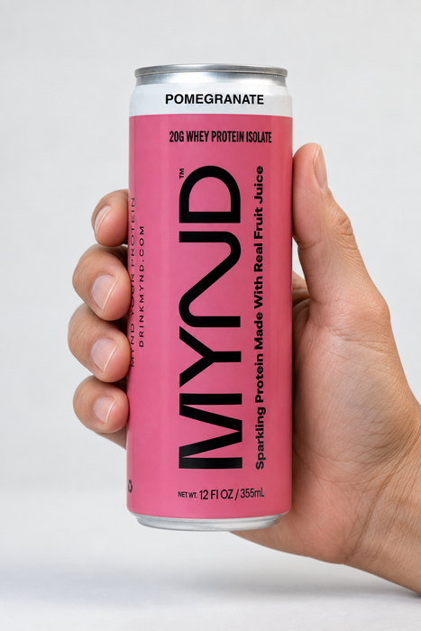 Hand holding a yellow can of MYND Pomegranate sparkling protein water with 20g whey protein isolate.