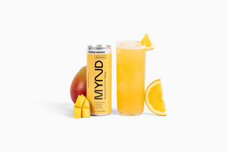 MYND Orange Mango drink can and glass with mangoes on a white background